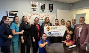 Providence Health Services team posing and holding the GrowFL Companies to Watch award banner with Russel Slappey from Nperspective Fractional CFO & Strategic Services.